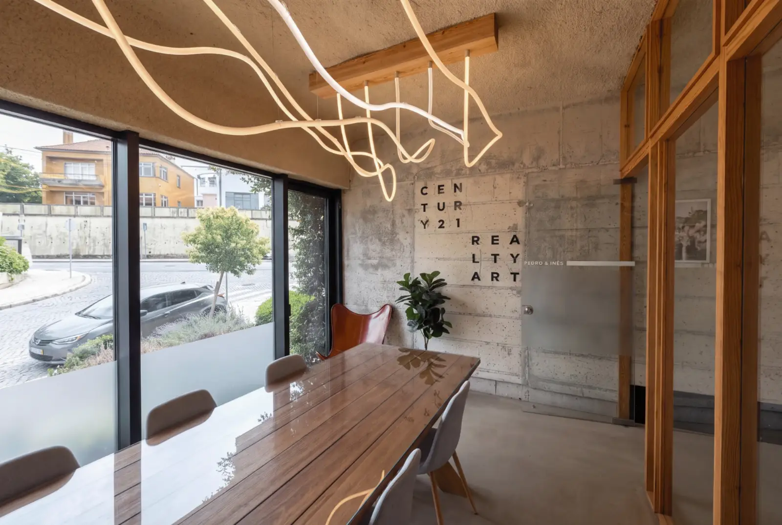Sala de reuniões da agência, com mesa de madeira e janela para a rua